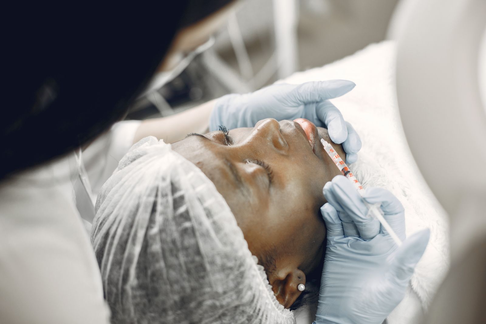 Woman receiving a facial filler injection in the lips at a medical aesthetics clinic